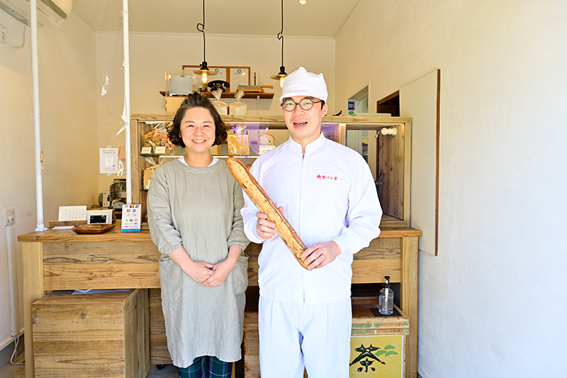 央製パン堂のパンを持って立つ梅澤夫婦