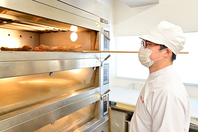 オーブンの前でパンを焼く梅澤様